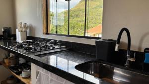 a kitchen with a sink and a stove and a window at Chalé Amanhecer in Aiuruoca