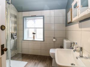 a bathroom with a sink and a toilet and a window at Driftwood Cottage in Heacham +28 photos