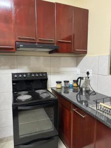 a kitchen with a black stove and wooden cabinets at Ekhaya Loft in Mbabane