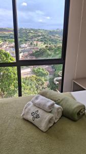 two towels sitting on a bed in front of a window at Flat 205 Zuppolini in Bananeiras