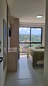 a bedroom with a bed and a large window at Flat 205 Zuppolini in Bananeiras