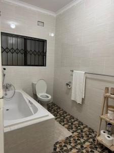 a white bathroom with a tub and a toilet at Ekhaya Loft in Mbabane +13 photos
