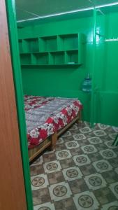 a bed in a room with a green wall at Linga Wooden Room Second floor in Kanchipuram