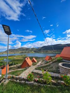 a sign in a field with a lake and houses at Alpine Lake Lodge Hotel in Cajamarca