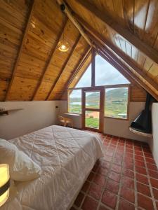 a bedroom with a bed and a large window at Alpine Lake Lodge Hotel in Cajamarca