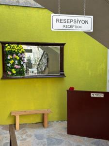 a mirror on the side of a yellow wall with a bench at Lokal Ayvalık Guest House in Ayvalık