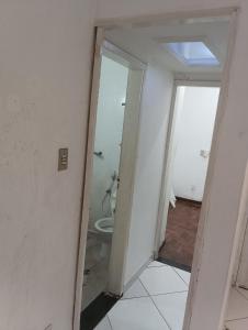 a bathroom with a toilet and a door to a room at Quarto 02 in Montes Claros