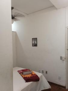 a white room with a bed with a pillow on it at Quarto 02 in Montes Claros