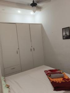 a white bedroom with white cabinets and a bed at Quarto 02 in Montes Claros