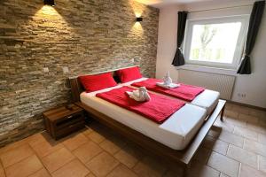 a bedroom with a bed with red pillows and two stuffed animals on it at Die Panorama-Wohnung-im-Grünem in Allensbach