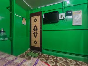 a green room with a door and a tv at Linga Wooden Room Second floor in Kanchipuram
