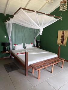 a bedroom with a bed with a canopy and a bench at Chez L'Avocatier in Sainte Marie