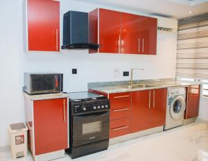 a kitchen with red cabinets and a stove at Billionaire Apartment in Lekki