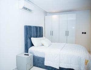 a bedroom with a bed with a blue headboard and white cabinets at Billionaire Apartment in Lekki