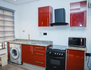 a kitchen with red cabinets and a washing machine at Billionaire Apartment in Lekki +15 photos