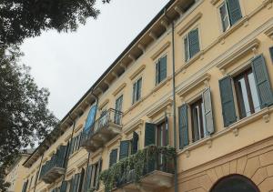 a yellow building with green shutters and a balcony at Lanza Luxury Home in Verona