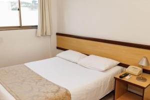 a hotel room with a bed and a telephone at Solar Flat Hotel in Juiz de Fora