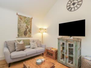 a living room with a couch and a flat screen tv at The Little Loft in Burford