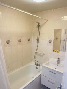 a bathroom with a bath tub and a sink at 8 mins Drive from Heathrow - Double bedroom in shared accommodation - Cavalier Gardens in Hillingdon