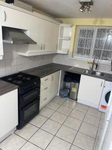 a kitchen with white cabinets and a black stove top oven at 8 mins Drive from Heathrow - Double bedroom in shared accommodation - Cavalier Gardens in Hillingdon