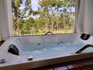 a bath tub with a view of a window at Pousada Anabela in Campo Alegre