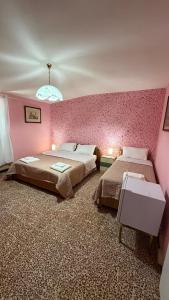 a bedroom with two beds and a pink wall at Casa Valeria in Pescia