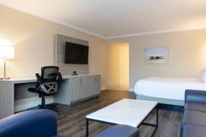 a hotel room with a bed and a desk with a chair at The Fredericton Inn in Fredericton