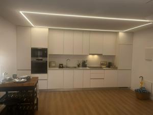 a kitchen with white cabinets and a wooden table at Casa de Saudade - Refúgio junto ao mar in Paço de Arcos