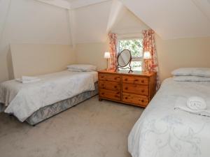 two beds in a room with a mirror and a dresser at Riverside Cottage in Llandrindod Wells