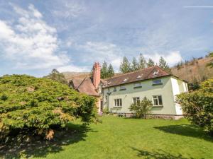 a white house with a chimney on a green yard at Riverside Cottage in Llandrindod Wells