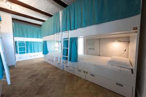 a bedroom with two bunk beds with blue curtains at Kite Hostel Stagnone in Marsala +115 photos