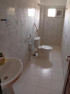 a white bathroom with a toilet and a sink at Chez Mounas in Saint-Louis