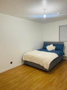a bedroom with a bed with a blue head board at 8 mins Drive from Heathrow - Double bedroom in shared accommodation - Cavalier Gardens in Hillingdon