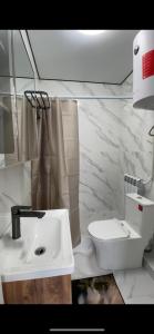 a white bathroom with a sink and a toilet at Karakol Aksuu guest house in Teploklyuchinskoye