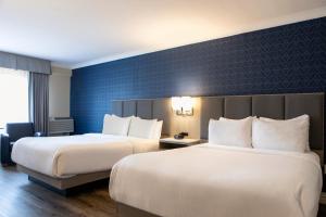 a hotel room with two beds and a blue wall at The Fredericton Inn in Fredericton +35 photos
