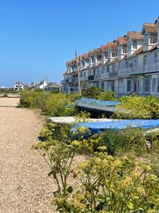 a row of boats sitting on the beach next to a building at The Dairy stylish chalet for 2 opp the beach 1 minute walk in Whitstable
