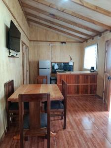 a dining room with a table and a kitchen at cabaña zoila N in Coñaripe