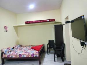 a bedroom with a bed and a tv and a chair at Close2heaven 3 bedroom privacy Home with a hall and a paid kitchen in Kodaikānāl