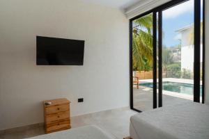 a bedroom with a flat screen tv on the wall at Mykonos Beach House Apartamentos By Jerusalema in Tolú