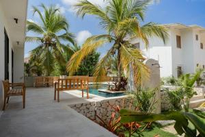 a patio with a bench and palm trees and a pool at Mykonos Beach House Apartamentos By Jerusalema in Tolú