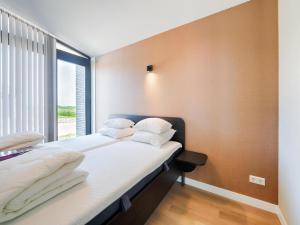 a bedroom with a bed with white pillows and a window at Leiden in Oud-Ade