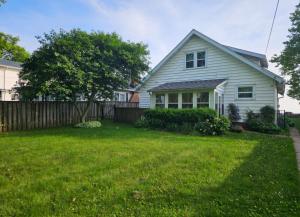 a white house with a fence and a yard at Casa Azul- Entire Lakefront Cottage with Hot Tub in Leamington