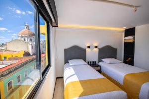 two beds in a room with a view of a city at Hotel Tamara in Puebla