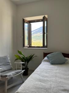 a bedroom with a bed and a chair and a window at La Scaletta - Charming Historic Center Home - Mountain View in San Nicola Arcella