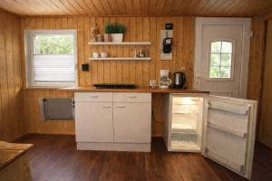 a kitchen with white cabinets and a wooden wall at Feriensiedlung Schwalbennest - Bungalows in Dranske +16 photos