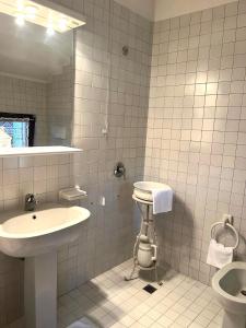 a white tiled bathroom with a sink and a toilet at Residenza Arilica - Silkeys in Peschiera del Garda +14 photos
