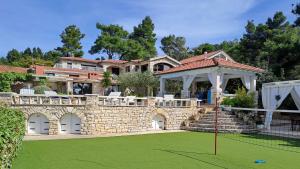 a large house with a stone wall and a putting green at Villa Stone House Poplat in Vela Luka