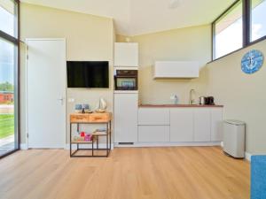 a kitchen with white cabinets and a tv on the wall at Kaag in Oud-Ade