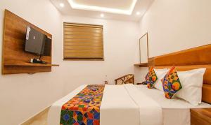 a bedroom with a bed with a tv on the wall at HOTEL AMBASSADOR SUKHNA LaKE in Chandīgarh