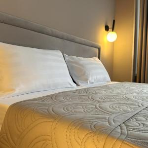 a bed with two white pillows and a lamp at SAFIA Hotel in Pavlodar